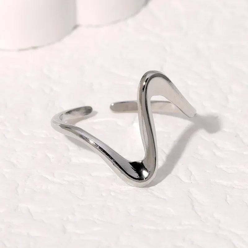 Flat lay of geometric wave ring in both finishes with jewelry props