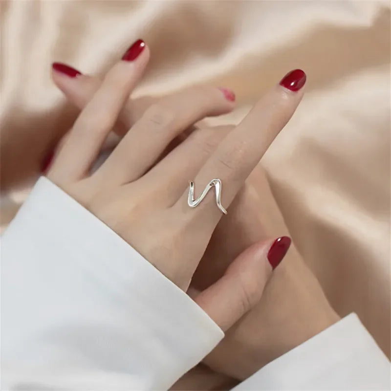 Model wearing gold wave ring with layered bracelets and soft lighting