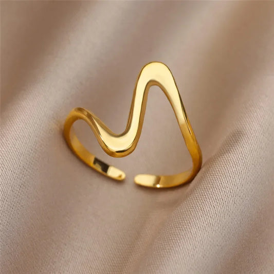 Close-up of gold wave ring with geometric curves on neutral background